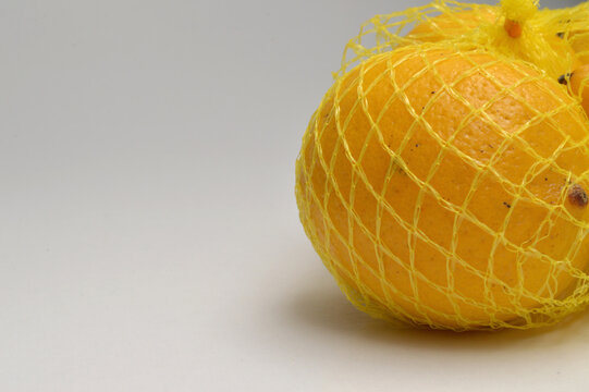 yellow lemon in a yellow mesh  on a white background corner composition horizontal layout, lemons close up with generous copy space,
