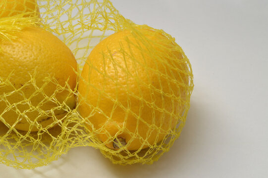 yellow lemon in a yellow mesh  on a white background corner composition horizontal layout, lemons close up with generous copy space,