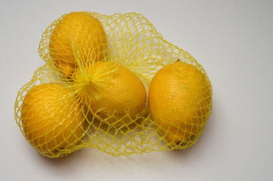 yellow lemon in a yellow mesh  on a white background cluster composition hoirzontal layout, lemons close up with generous copy space,