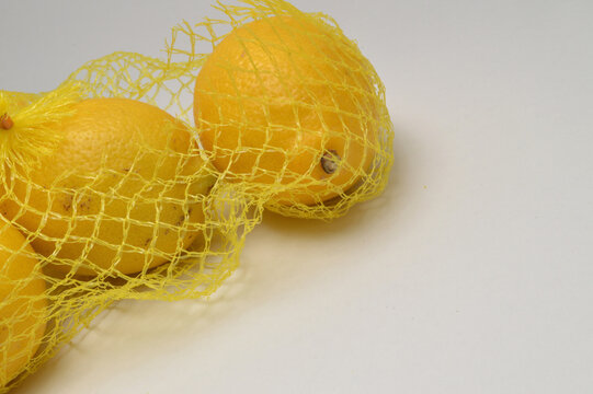 yellow lemon in a yellow mesh  on a white background corner composition horizontal layout, lemons close up with generous copy space,