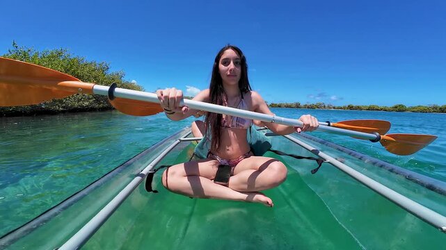 Kayak-mounted camera view of young women paddling across the pristine lagoon of Francisqu&iacute;, showcasing crystal-clear Caribbean waters in Los Roques, Venezuela