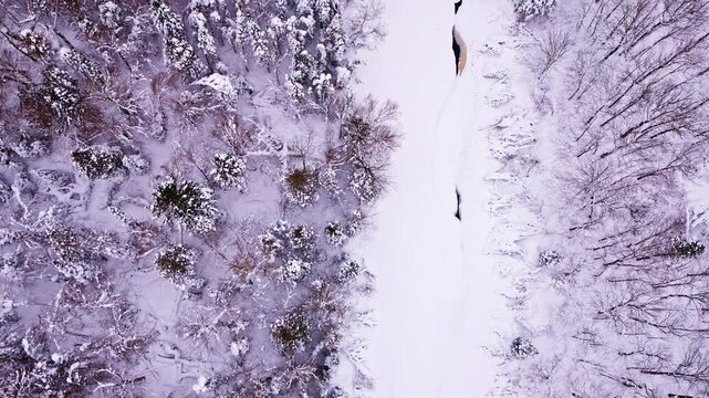 Drone footage capturing a frozen winter landscape divided by a flowing river.