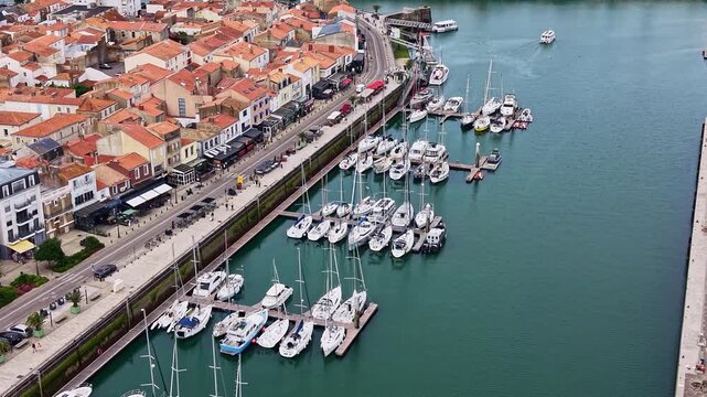 Tilted drone shot of busy Captaincy of Marinas lined with yachts near Quai Ernest de Franqueville avenue and waterfront buildings, Les Sables-d&rsquo;Olonne, Vend&eacute;e, France