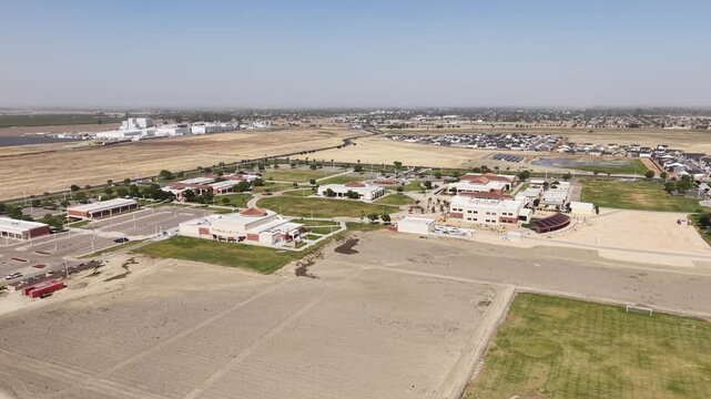 Aerial zoom in over the campus of West Hills College Lemoore in California's Central Valley, showing the buildings, parking lot, and surrounding arid landscape