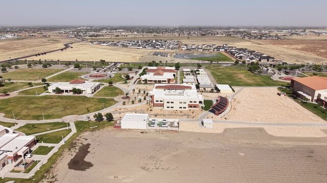 Aerial perspective showing the Lemoore College campus, its buildings, parking lots, and the surrounding residential area in the dry landscape of California's Central Valley on a sunny day
