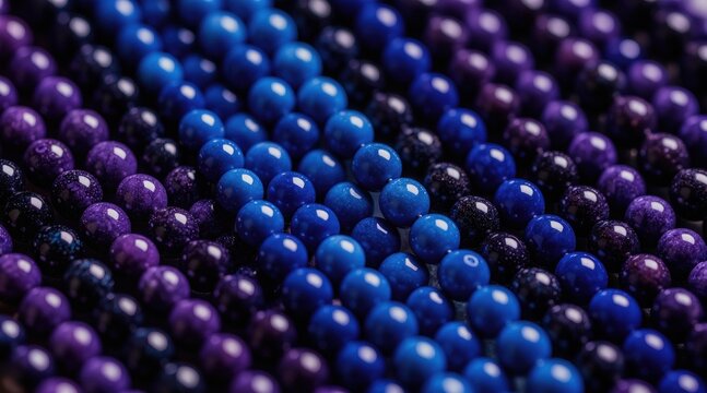 Rows of shiny beads in gradient shades of blue and purple. Smooth spherical objects arranged in neat lines create a beautiful textured pattern. Ideal for jewelry or craft backgrounds.