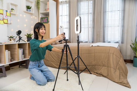 Young Content woman Setting Up Smartphone and Ring Light for Live Streaming, Vlogger Creating Social Media Content in Bedroom Studio