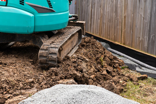 Excavator positioned on a mound of soil and rocks