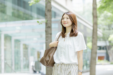 Fototapeta premium 緑豊かなオフィス街を歩く日本人女性のライフスタイル
