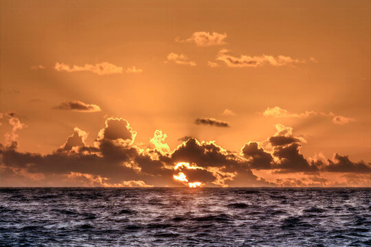 Sun rising through clouds over Atlantic Ocean