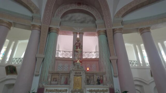 Cinematic interior tilt up of the unique violin-shaped Saint Didier church in Asfeld France revealing altar statue and dome