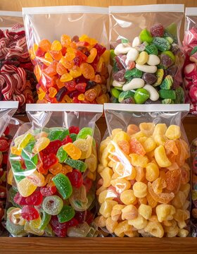 A wooden shelf stocked with clear plastic bags filled with various colorful candies