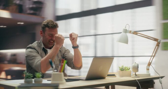 360 Degree. Man Using Laptop Computer and Boosting Productivity in Office, Celebrating and Smiling After Optimising Workflow and Reaching Business Goal at Desk. Orbital Arc Tracking Shot.