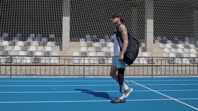 Young sportsman with bionic leg prosthesis walks along track