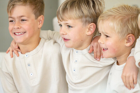 Young boys sitting on the couch with arms over each others shoulder