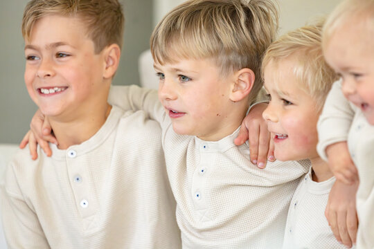 Young boys sitting on the couch with arms over each others shoulder