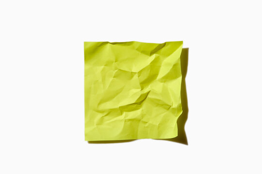 Crumpled yellow post it note on white background