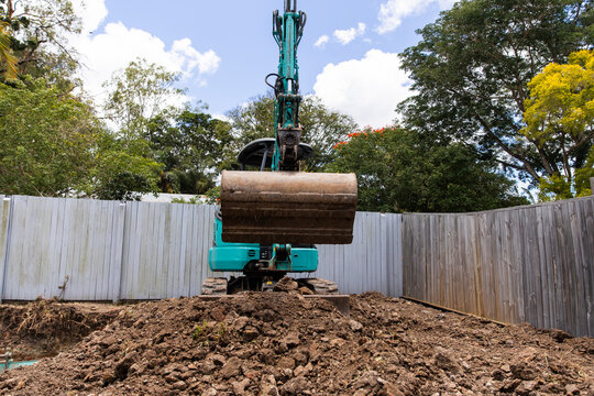 Excavator positioned on a mound of soil and rocks with bucket lowered down