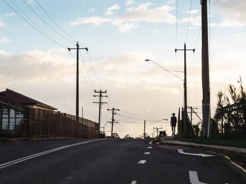 Quiet suburban street with power lines and person walking