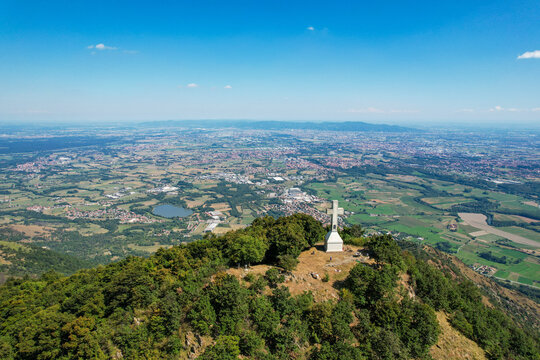 Aerial view of the Monte Musine summit featuring the Croce del Musine monumental cross overlooking the Susa Valley and the surrounding plains near Caselette, Piedmont, Italy.