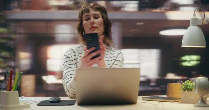 360 Degree. Woman Reviews Analytics on Laptop, Then Uses Smartphone to Manage Ecommerce Business, Tracking Sales Data and Digital Growth Metrics in Creative Office. Orbital Cinematic Arc Tracking Shot
