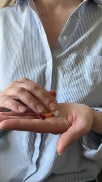 Woman keeping in hand different colorful pills and tablets close up. Taking daily dose of vitamins and supplements, home treatment, woman's health, healthcare and medicine, biohacking.