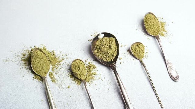 Green tea matcha powder on spoons with scattered dust