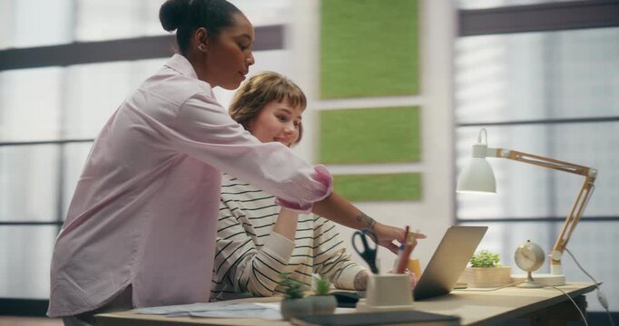 360 Degree. Diverse Female Team Reviews Ecommerce Analytics on Laptop in Office, Black Manager Talks to Caucasian Colleague Through Sales Data and Payment Software. Orbital Cinematic Arc Tracking Shot