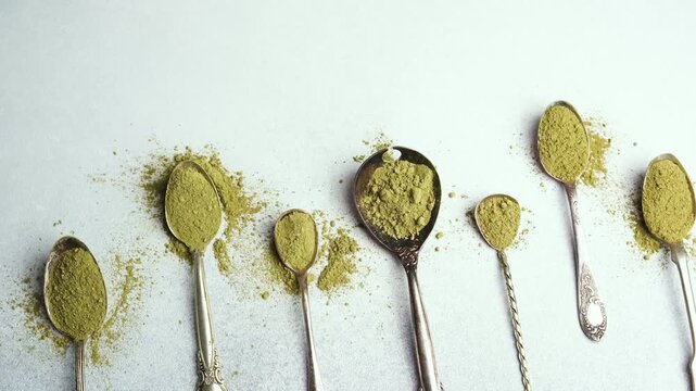 Powdered matcha tea fills spoons on a white surface