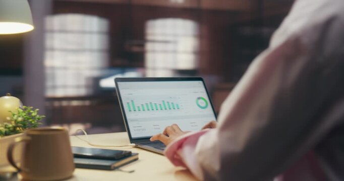 360 Degree. Focused Mixed Race Businesswoman Works on Laptop in Office, Reviewing Sales Documents and Ecommerce Data, Driving Digital Innovation and Productivity. Orbital Cinematic Arc Tracking Shot.