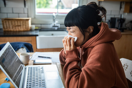 Sick woman working from home in kitchen