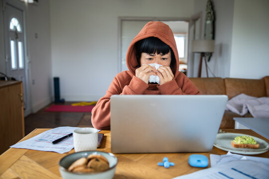 Sick woman working from home at kitchen table