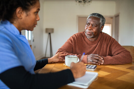 Caregiver consoling senior man during home visit