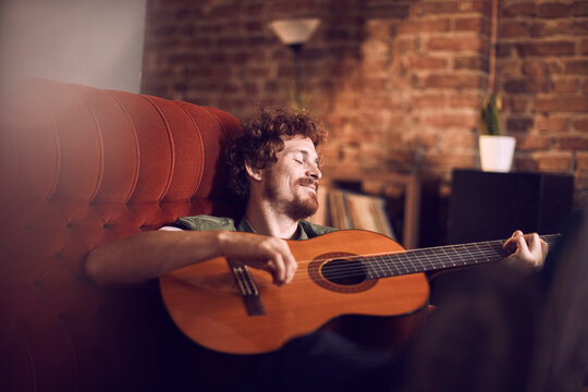 Relaxed man playing acoustic guitar at home