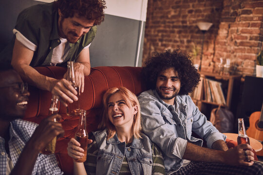 Young friends toasting beer bottles at home