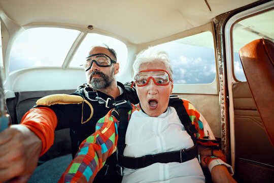 Senior woman and instructor preparing for tandem skydive inside small plane