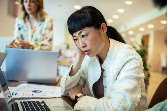 Stressed businesswoman analyzing data on laptop in modern office