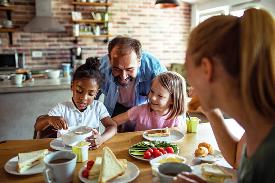 Parents and children eating healthy breakfast in home kitchen