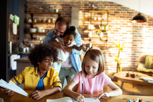 Parent helping kids with homework in home kitchen