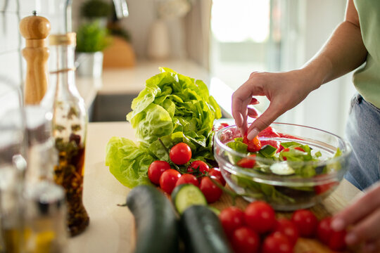 Person preparing fresh salad in home kitchen