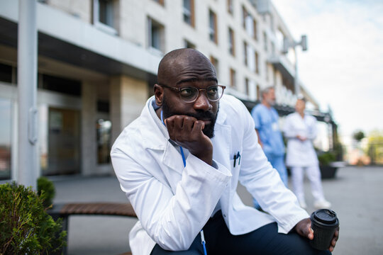 Tired doctor with coffee outside hospital