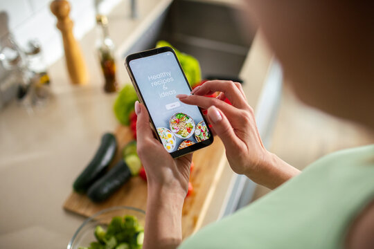Woman using recipe app on smartphone in home kitchen