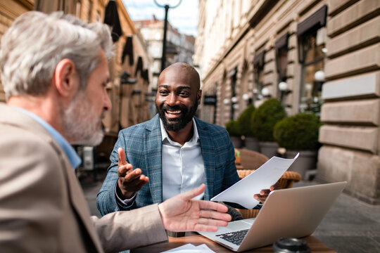 Two businessmen meeting with laptop at outdoor cafe