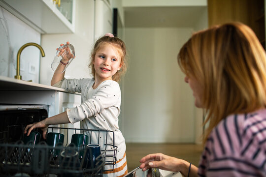 Mother and daughter loading a dishwasher in a home kitchen