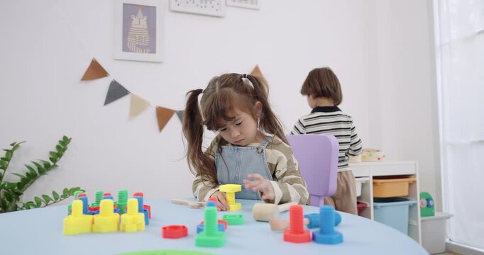 Asian preschool girl sort peg block stack on blue table, compare color height, Montessori education activity, bright window light, daycare classroom, early math skill, calm study concept, practice.
