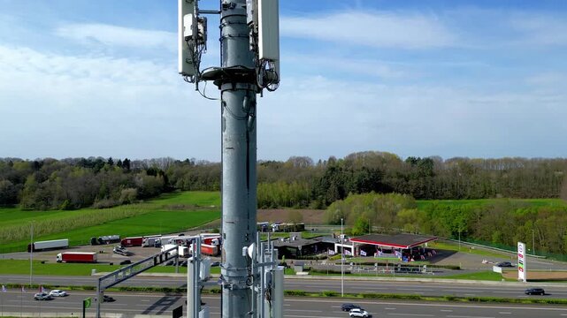 Aerial Drone Orbit Around 5G Cell Tower with Highway Rest Stop and Green Countryside in Background