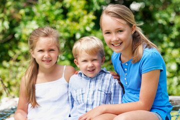 Fototapeta premium Family, children and portrait in park with love, sibling care and relationship development with smile. Boy, sisters and outdoor with happiness for support, bonding and together for summer holiday