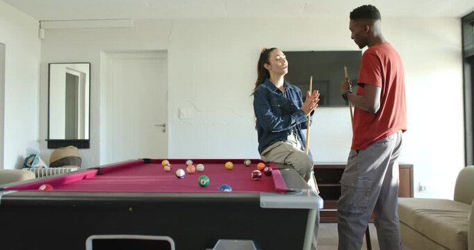 Couple home talking, African American man urging woman adjusting cue on red-felt table, copy space