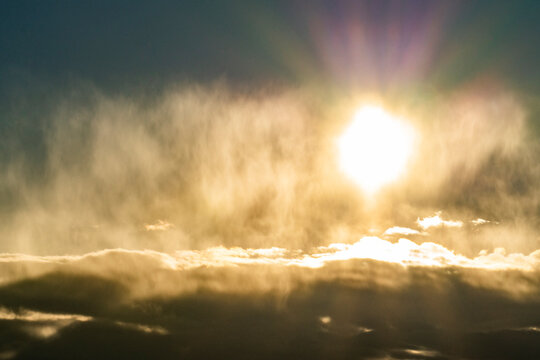 Sun glowing above cloud bank
