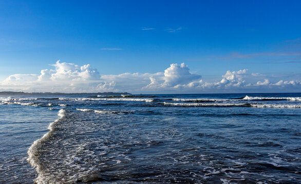 Puffy clouds above calm sea at dawn